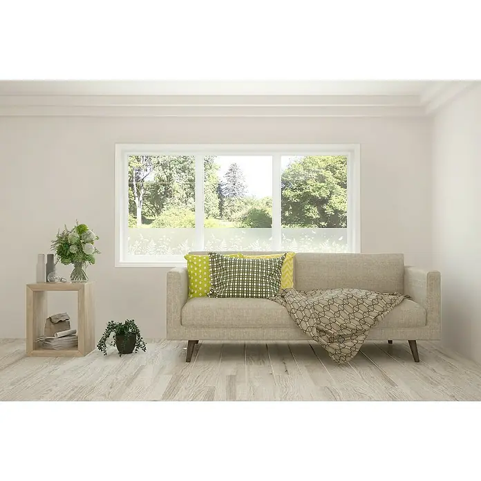 D-c-fix Static Glasfolie Meadow - 150 x 20 cm, Transluzent, Statisch haftend - Das Bild zeigt eine gemütliche Inneneinrichtung mit einem beigen Sofa, bunten Kissen und einem Fenster mit Blick auf üppiges Grün, das eine entspannende Atmosphäre schafft.