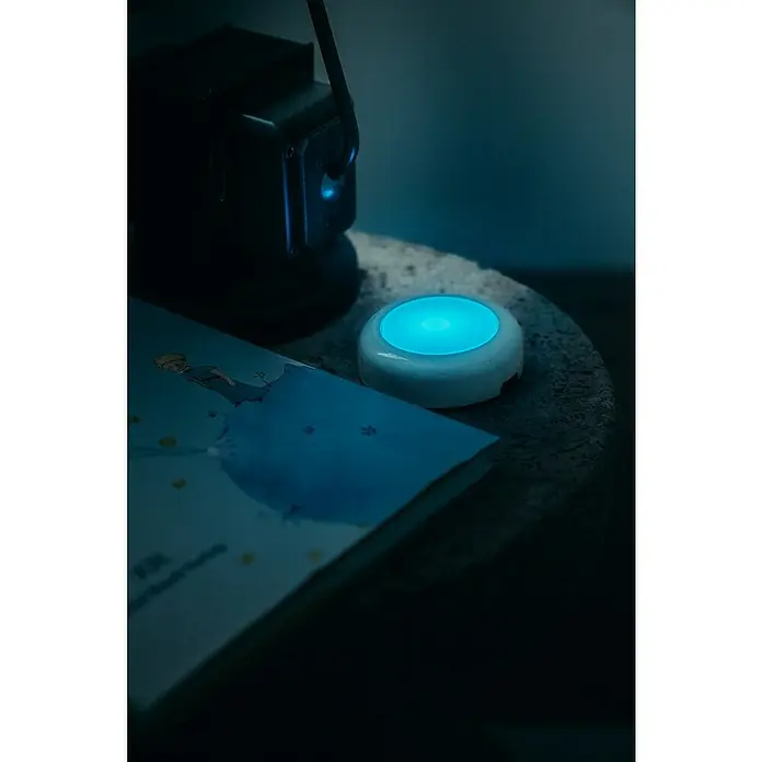 Osram Luz de armario LED Dot-It Twist & Shake - 1 luz, 0,5 W, Blanco - Primer plano de una mesita de noche con una edición del libro El Principito, una lámpara y un altavoz.