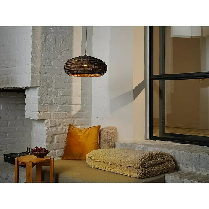 Ledvance Lámpara colgante redonda Cardboard - 40 W, Ø x Al: 40 x 125 cm, Marrón, E27 - Una lámpara colgante moderna hecha de material tejido cuelga sobre una acogedora zona de estar con cojines y una manta, creando un ambiente cálido.