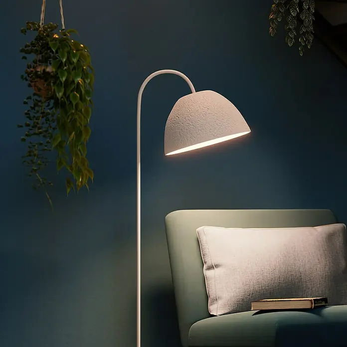 Ledvance Lámpara de pie Camel Bell - 40 W, Altura: 153 cm, Blanco, E27 - Elegante lámpara de pie con luz suave junto a un sillón verde con cojín y libro. Plantas de interior al fondo.