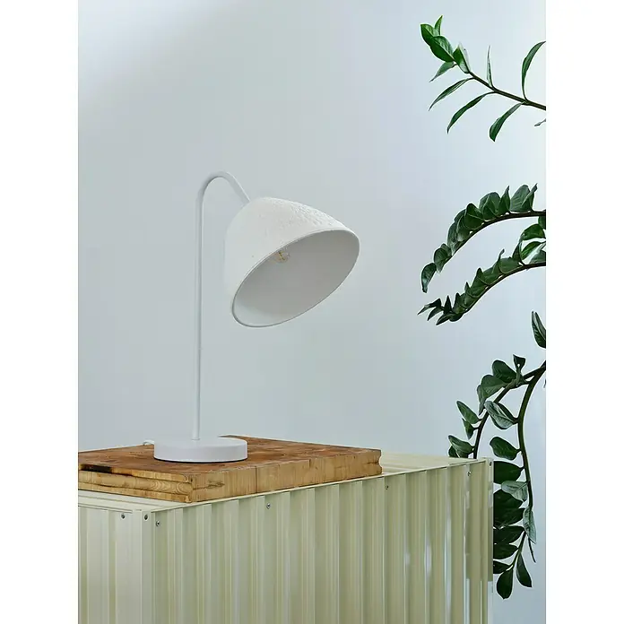 Ledvance Lámpara de sobremesa redonda Camel Bell - 40 W, Ø x Al: 33,5 x 46 cm, Blanco, E14 - Primer plano de una lámpara de escritorio blanca sobre una tabla de madera colocada sobre un armario beige con paneles acanalados.