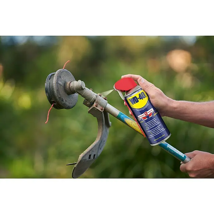 WD-40 Multiöl Smart Straw - 200 ml - Sprühdose WD-40 wird auf einen Rasentrimmer aufgetragen, um ihn zu warten und zu schmieren.