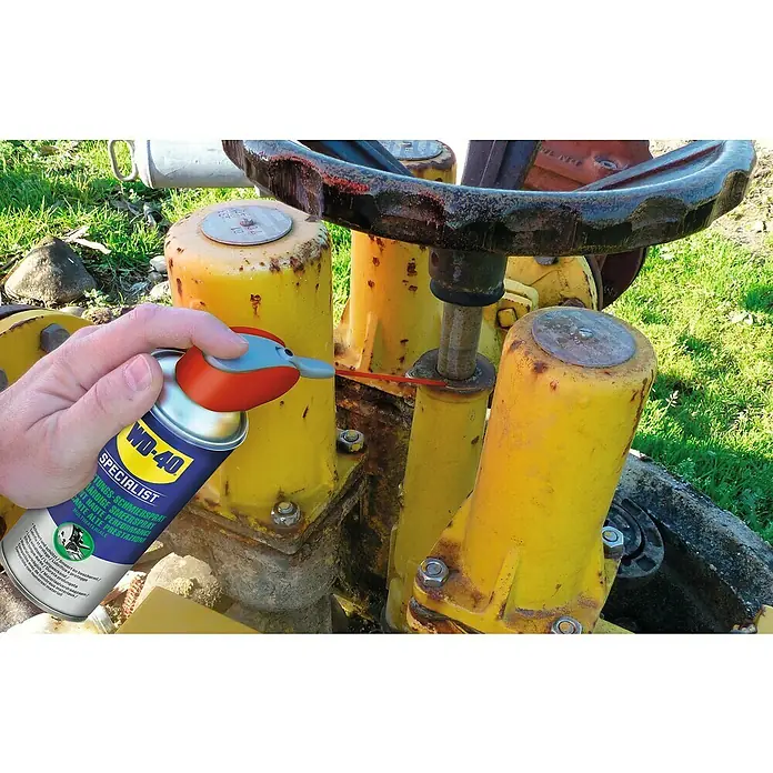 WD-40 Specialist PTFE-Schmiermittel Hochleistungsspray Smart Straw - 300 ml - Eine Dose WD-40 Specialist wird auf ein gelbes, metallisches Maschinenteil gesprüht, um es zu schmieren und die Funktionalität zu verbessern.