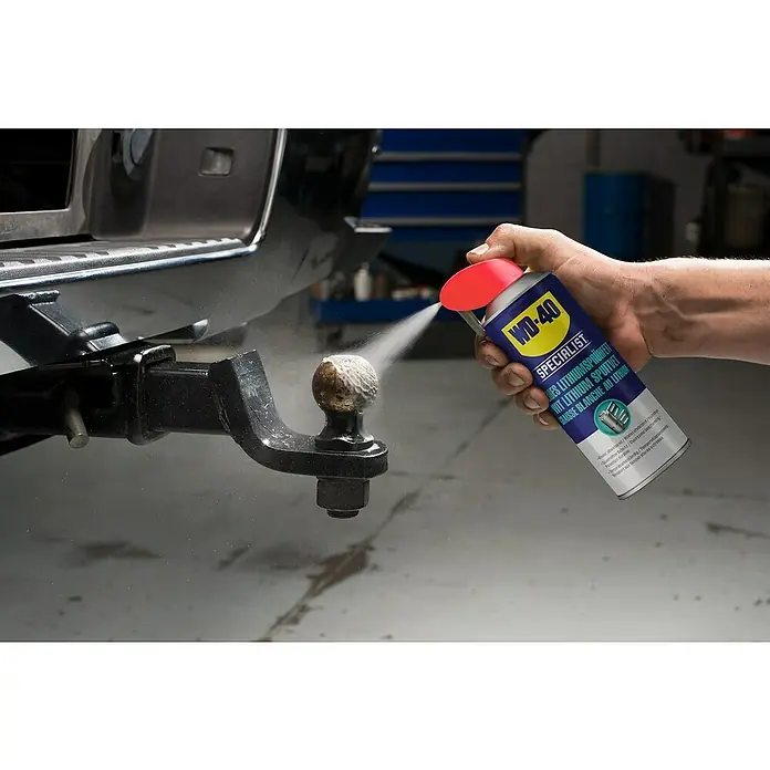 WD-40 Specialist Lithiumsprühfett Smart Straw - Weiß, 300 ml - Detailaufnahme von WD-40 Spezialist Lithium-Sprühfett beim Auftragen auf eine Anhängerkupplung, um diese zu schmieren und vor Verschleiß zu schützen.