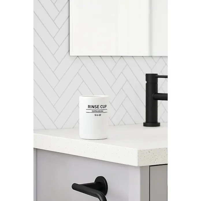 Aquasanit Ink Portacepillos - L x An x Al: 7 x 7 x 104 cm, Cerámica - Primer plano de una taza blanca con la etiqueta "Rinse Cup" y "Toothbrush" en el baño, al lado del grifo y el toallero.