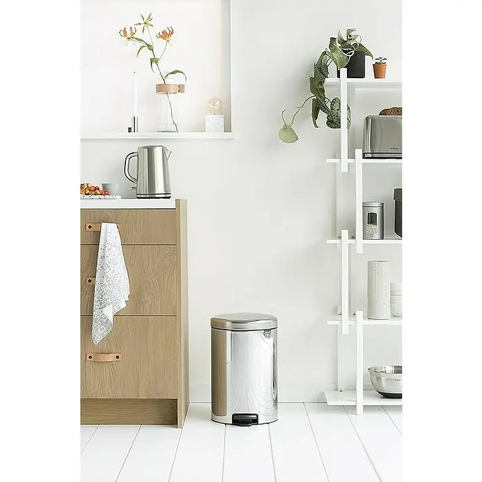 Proregal Treteimer Brabantia Klassischer Tretmülleimer mit Soft-Verschluss - 20 l, Metall, Edelstahl - Nahaufnahme eines polierten, zylindrischen Treteimers aus Edelstahl neben einem hellen Holzschrank auf einem hellen Holzboden.