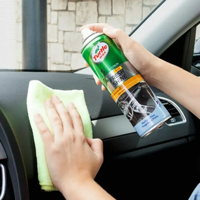 Turtle Wax Spray para salpicadero - Pino, 500 ml - La imagen muestra a una persona aplicando Turtle Wax Fresh Shine al salpicadero de un coche con un paño para la limpieza.