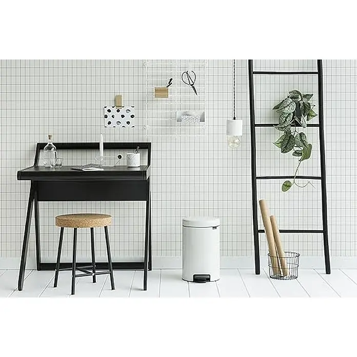 Proregal Treteimer Brabantia Klassischer Tretmülleimer mit Soft-Verschluss - 12 l, Metall, Weiß - Minimalistischer Arbeitsbereich mit schwarzem Schreibtisch, Korkhocker und weißem Papierkorb vor einer Fliesenwand.