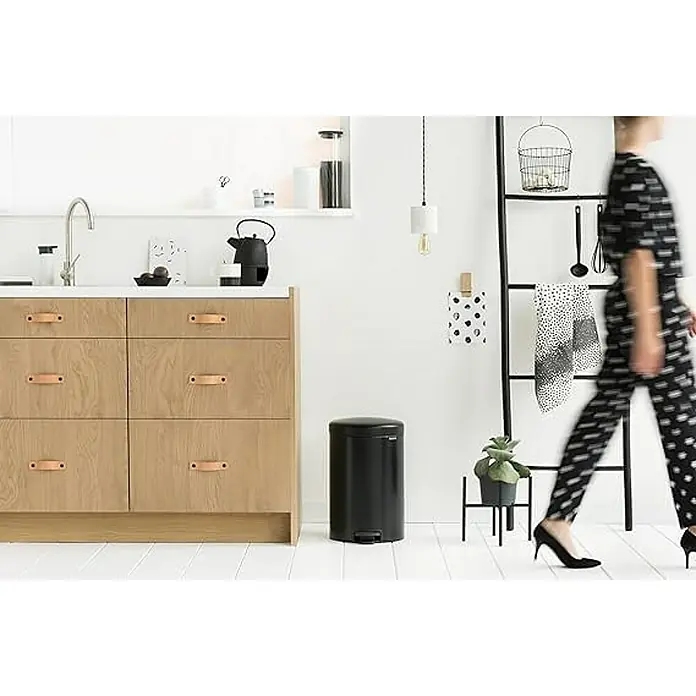 Brabantia Klassischer Tretmülleimer mit Soft-Verschluss | 20 Liter, HxBxT 46,7x29x38cm | Metall | Metallik Schwarz -  - Ein stilvoller Küchenbereich mit einem schwarzen Abfalleimer mit Fußpedal als zentrales Element, der Funktionalität und modernes Design vereint.