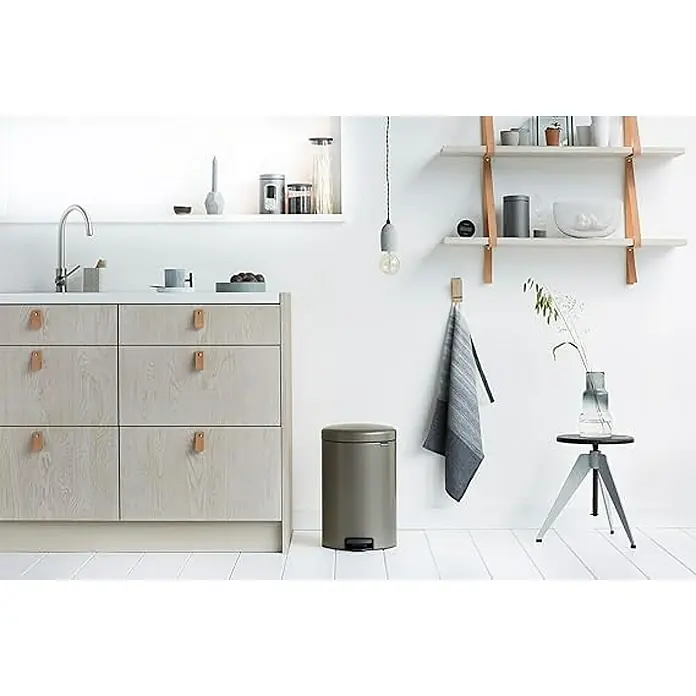 Proregal Treteimer Brabantia Klassischer Tretmülleimer mit Soft-Verschluss - 20 l, Metall, Platin - Ein stilvolles Kücheninterieur mit hellen Holzschränken, einem runden Mülleimer und dekorativen Regalen an der Wand.