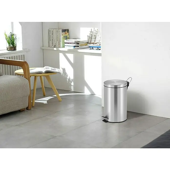 Proregal Treteimer Runder Tretabfallsammler mit herausnehmbaren Kunststoff-Inneneimer - 12 l, Metall, Matt Silber - Ein eleganter, silberfarbener Treteimer aus Edelstahl steht in einem hellen Raum mit Fliesenboden und ergänzt das moderne Interieur.