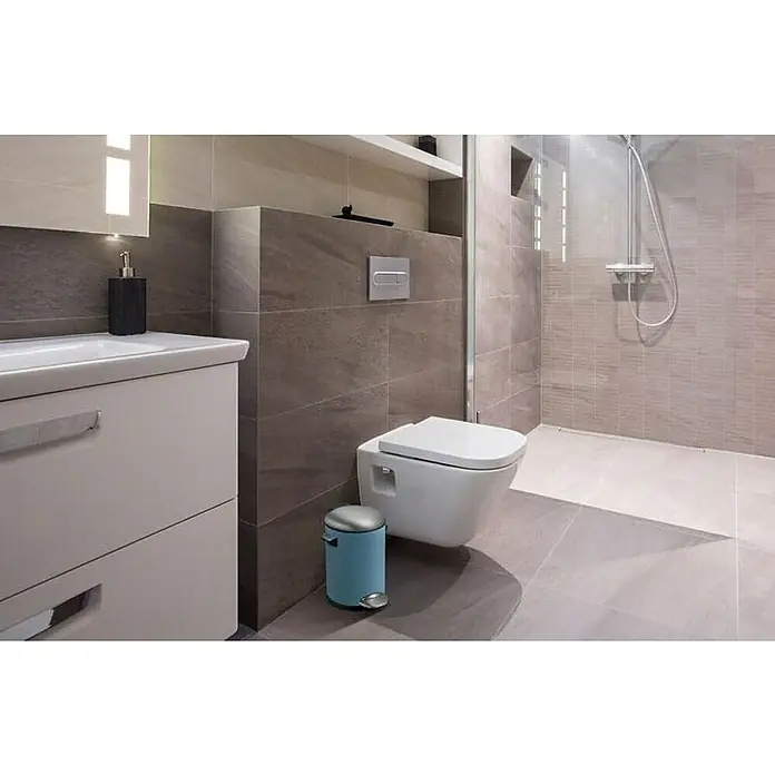 Proregal Treteimer Retro Treteimer mit markanten Griffen und Kugelkappe - 3 l, Kunststoff, Hellblau - Ein modernes Badezimmer mit einer stilvollen Toilette, einem Waschbecken mit Unterschrank und einem blauen Mülleimer, die ein harmonisches Gesamtbild ergeben.