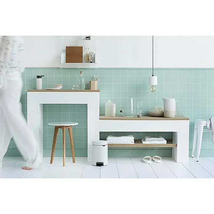 Proregal Treteimer Brabantia Klassischer Tretmülleimer mit Soft-Verschluss - 3 l, Metall, Weiß - Ein Badezimmer mit mintfarbenen Fliesen und weißen Möbeln. Ein runder Hocker steht neben einem weißen Waschtisch.