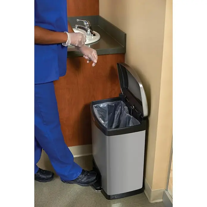 Proregal Treteimer Rechteckiger Treteimer aus gebürstetem Edelstahl - 45 l, Edelstahl, Silber - Ein Gesundheitsdienstleister entsorgt Handschuhe in einem grauen, rechteckigen Treteimer mit zwei Fächern und einem Edelstahldeckel.