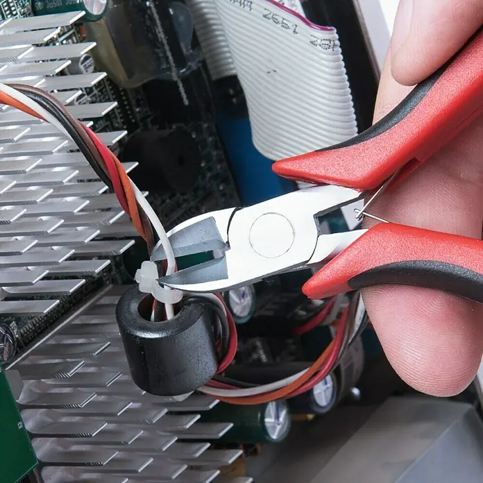 Connex Alicate de corte diagonal - Largo: 11 cm - Primer plano de unos alicates cortando una brida en un dispositivo electrónico, destacando la precisión y el trabajo de reparación.