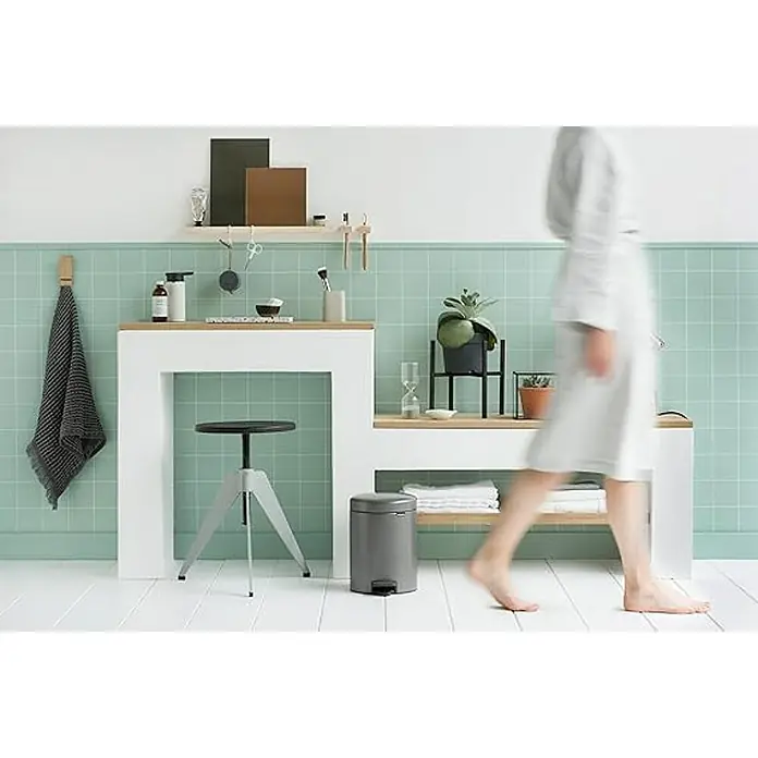 Proregal Treteimer Brabantia Klassischer Tretmülleimer mit Soft-Verschluss - 5 l, Metall, Platin - Badezimmer mit mintgrünen Fliesen, weißem Waschtisch mit Eichenplatte, grauem Treteimer und verschwommener Person.