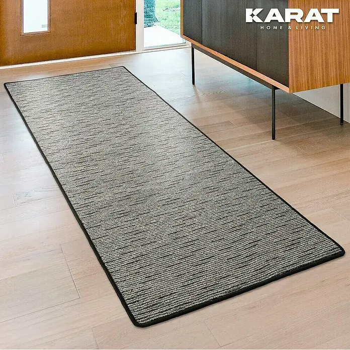 Flachgewebeteppich Geneva - Anthrazit, 200 x 200 cm, 100 % Polypropylen - Bild einer grauen, länglichen Fußmatte von Karat Home & Living auf einem hellen Holzboden.