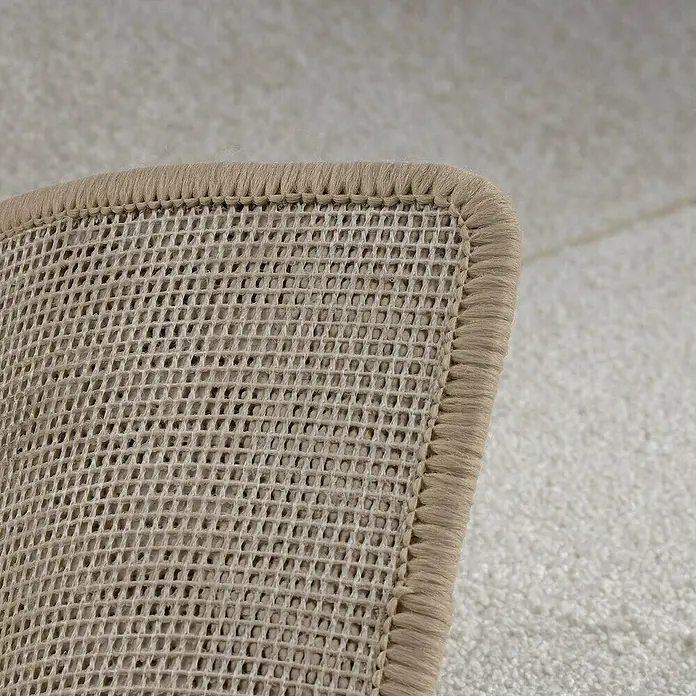Kurzflorteppich Sundae - Creme, 200 x 200 cm, 100 % Polypropylen - Detailaufnahme einer beigen Teppichunterlage mit rutschfester Netzstruktur und eingefasstem Rand für sicheren Halt auf glatten Böden.