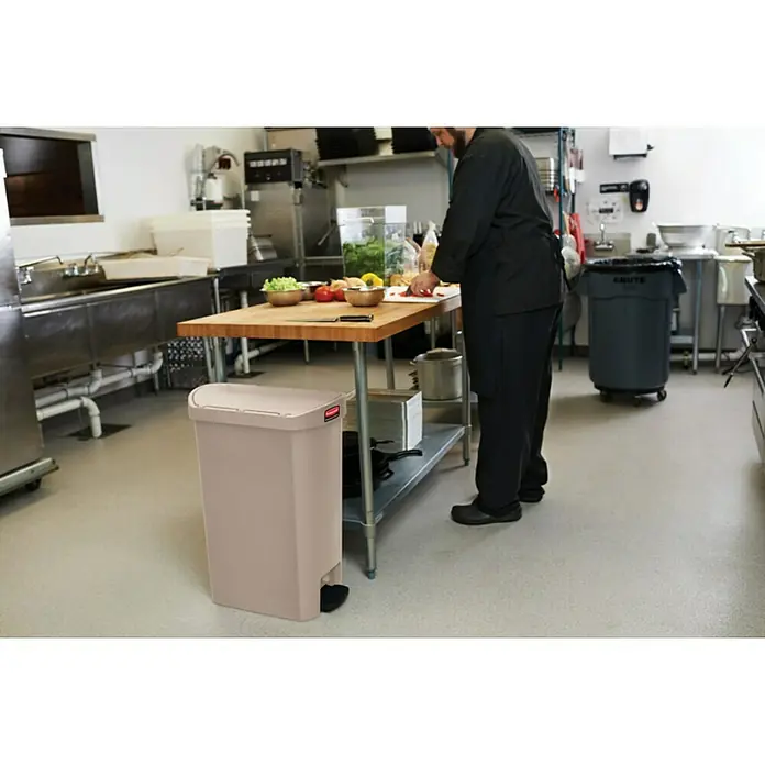 Proregal Treteimer Rubbermaid Slim Jim Step On Container End Step Pedal-Abfalleimer - 50 l, Kunststoff, Beige - Ein beigefarbener Rubbermaid-Treteimer steht in einer Großküche. Der Eimer hat einen Deckel und ein Pedal.