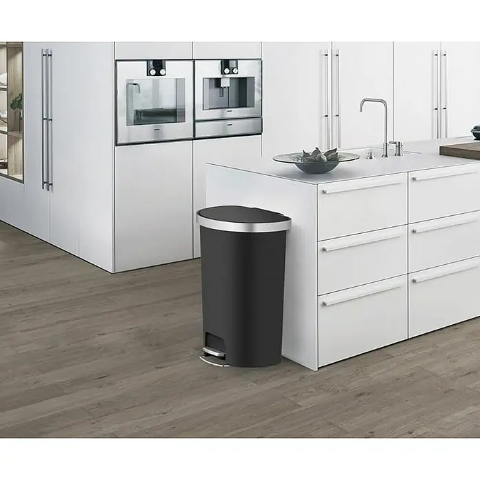 Proregal Treteimer Halbrunder Funktionale Treteimer aus Kunststoff mit Soft-Close-Deckel - 55 l, Kunststoff, Schwarz - Schwarzer Treteimer mit silbernem Rand neben einer weißen Kücheninsel mit Spüle und Schubladen in einer modernen Küche.