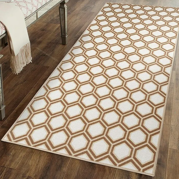 Teppichläufer Cardiff - Braun/Beige, 250 x 80 cm, 100 % Polyamid - Ein rechteckiger Teppich mit sechseckigem Muster in Braun- und Beigetönen, der auf einem Holzboden liegt, verleiht jedem Raum einen modernen Touch.