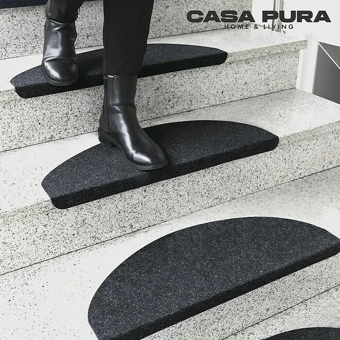 Stufenmatte Leipzig - 64 x 21 cm, Anthrazit, Halbrund - Bild einer Person, die eine Treppe mit schwarzen, halbmondförmigen Casa Pura Stufenmatten hinaufgeht.