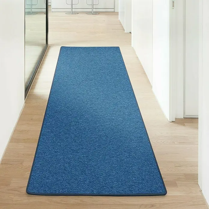 Flachgewebeteppich London - Dunkelblau, 200 x 200 cm, 100 % Polypropylen - Blauer Teppichläufer auf einem hellen Holzboden in einem Flur. Der Läufer hat eine dunkle Umrandung und eine feine Textur.