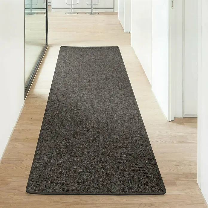 Flachgewebeteppich London - Dunkelbraun, 100 x 100 cm, 100 % Polypropylen - Ein langer, dunkelgrauer Läufer liegt auf einem hellen Holzboden in einem modernen Flur. Der Teppich bietet Komfort und Stil.