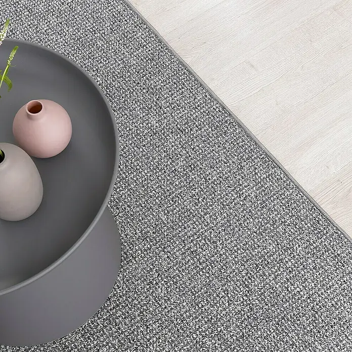 Flachgewebeteppich Carlton - Hellgrau, 200 x 200 cm, 100 % Polypropylen - Ein grauer Teppich liegt neben einem Holzboden und einem grauen Tisch mit rosa Vasen. Dekoratives Wohnaccessoire.