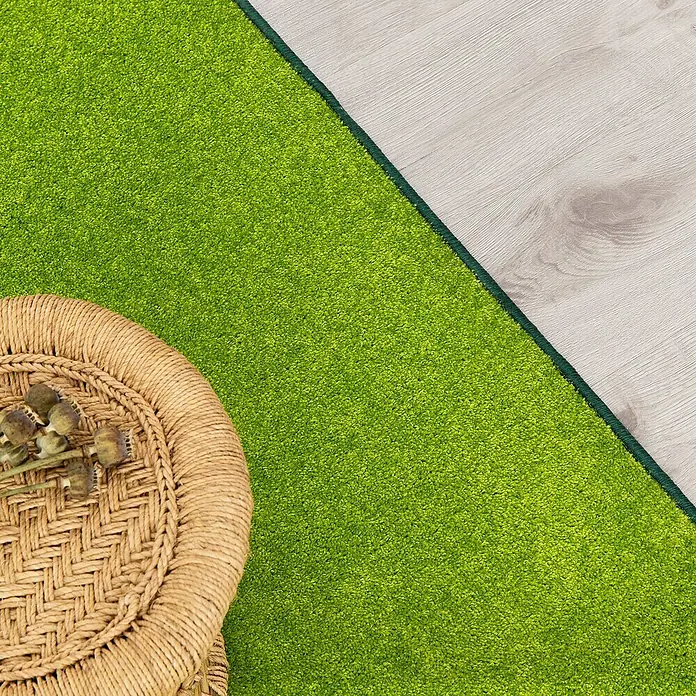 Kurzflorteppich Dynasty - Grün, 200 x 200 cm, 100 % Polypropylen - Nahaufnahme eines grünen Teppichs mit einer braunen Korbdekoration und einem Teil eines hellen Holzfußbodens.