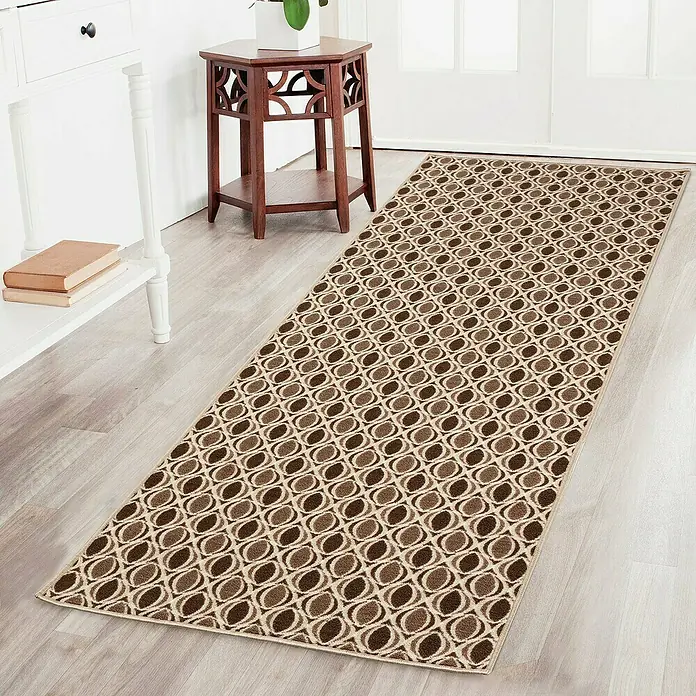 Teppichläufer Cork - Braun, 150 x 80 cm, 100 % Polyamid - Ein brauner Läuferteppich mit einem sich wiederholenden Kieseldesign liegt in einem Eingangsbereich auf einem Holzboden.