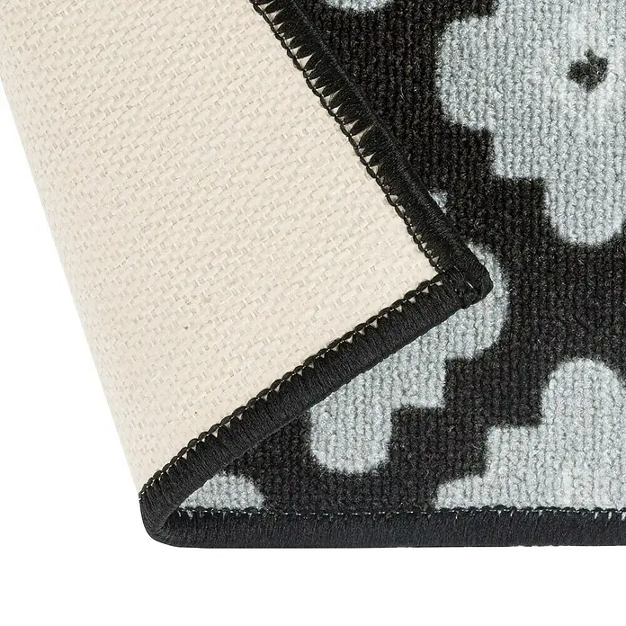 Teppichläufer Sligo - Schwarz/Grau, 500 x 80 cm, 100 % Polyamid - Detailansicht einer Fußmatte mit abstraktem Blumenmuster und schwarzer Umrandung, die die Textur und Verarbeitung hervorhebt.