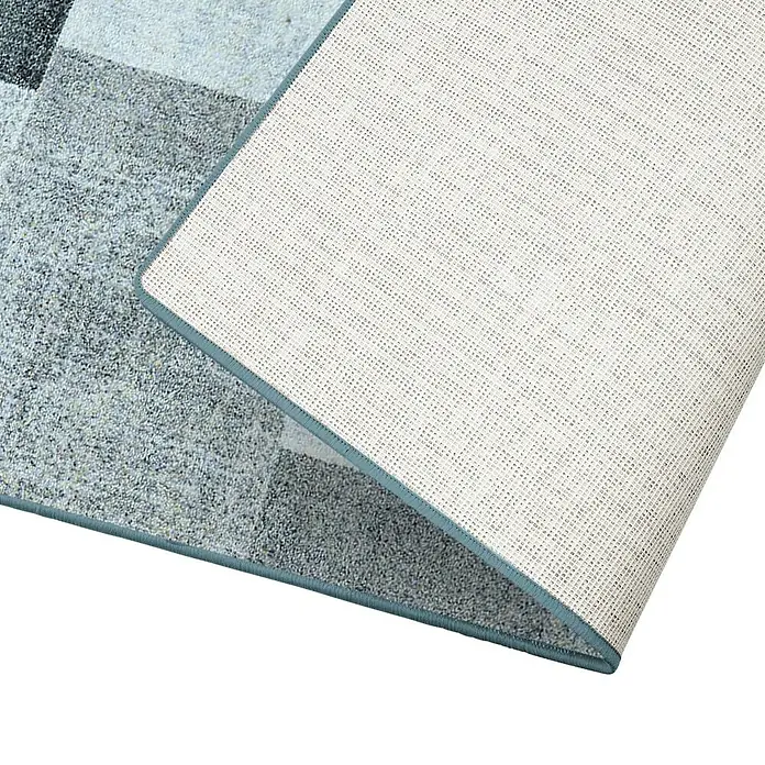Teppichläufer Lucano - Anthrazit, 350 x 80 cm, 100 % Polyamid - Nahaufnahme einer grauen Teppichunterseite mit blauem Rand, die eine rutschfeste Textur zeigt und für zusätzliche Sicherheit sorgt.