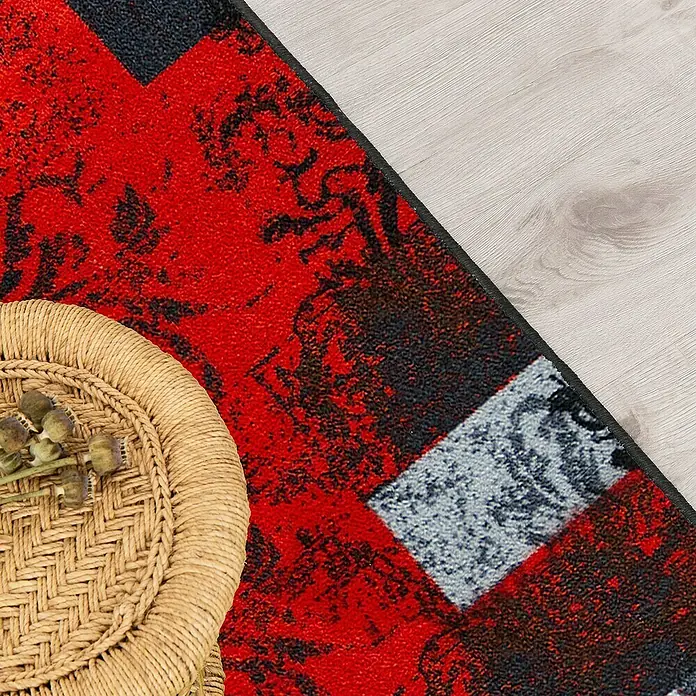 Teppichläufer Maraba - Rot, 200 x 80 cm, 100 % Polyamid - Nahaufnahme eines roten Teppichs mit abstraktem Muster und einer braunen Korbschale. Der Teppich liegt auf einem hellen Holzboden.