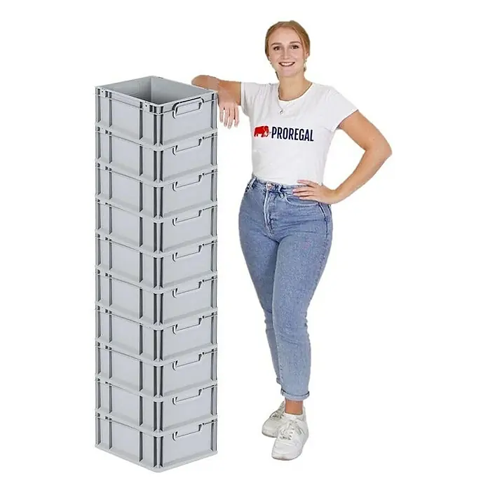 Proregal Euroboxen-Set 10x Eurobox NextGen Economy mit Scharnierdeckel und roten Verschlüssen - Kunststoff, Grau, 10 Stk. - Ein hoher Stapel grauer Lagerboxen von PROREGAL neben einer Frau, ideal für Lagerung und Organisation in Werkstatt oder Büro.