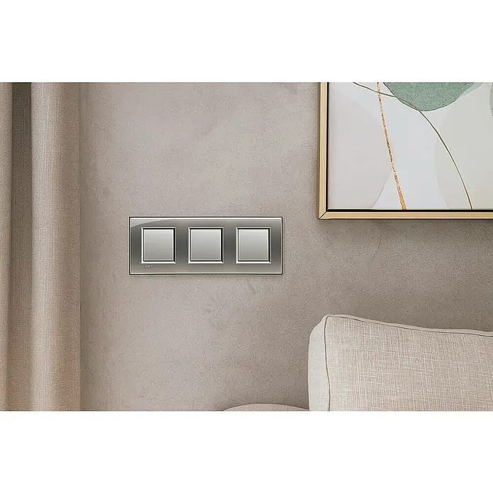 Bticino Living Light Marco - Aluminio / Plata, Modelo de mecanismos: x 3, Plástico, Instalar - Combinación triple de interruptores de luz GIRA de material brillante, montada en una pared texturizada con cortina y obra de arte.