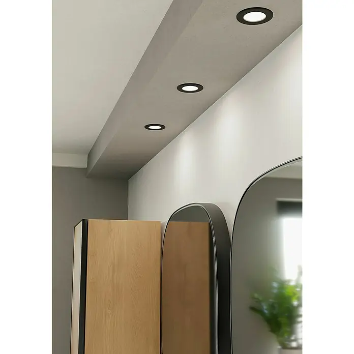 Eglo Fueva 6 Downlight empotrable LED redondo - 3,5 W, Ø x Al: 8,6 x 3,1 cm, Negro, 2.700 K - 6.500 K, IP44 - Tres modernas luces LED empotradas en el techo, redondas con borde negro, iluminan un pasillo con una pared blanca y diseño minimalista.