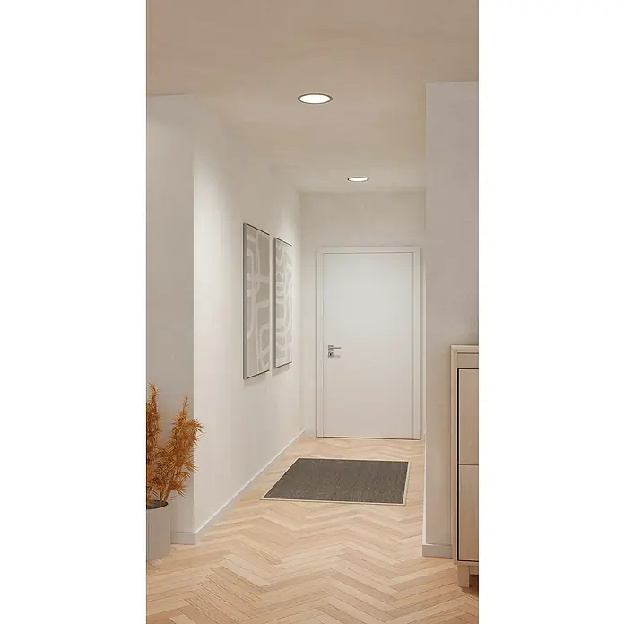 Eglo Fueva 6 Downlight empotrable LED redondo - 12 W, Ø x Al: 21,6 x 3,1 cm, Níquel, 2.700 K - 6.500 K, IP20 - Vista a un pasillo con parqué de espiga clara, paredes blancas y dos pinturas abstractas. Dos luces de techo redondas proporcionan iluminación.