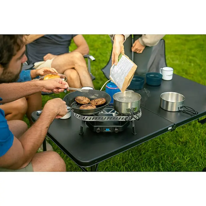Campingaz Campingkocher Camp & Trek Twin Connect CV - Anzahl Brenner: 2 Stk., 2 kW - Campingküche im Freien: Burger braten und Wasser kochen auf einem Campingtisch mit Kocher für ein gemütliches Outdoor-Erlebnis.
