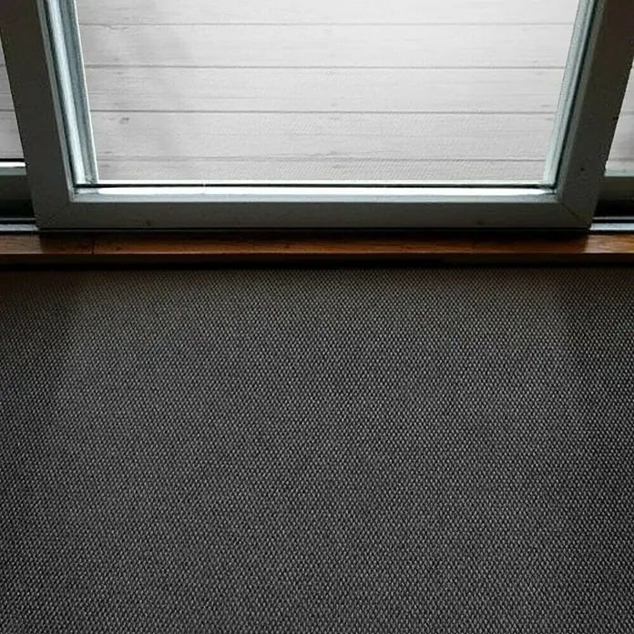 Schmutzfangmatte Hong Kong - Anthrazit, 1.100 x 200 cm, 100 % Polypropylen - Detailaufnahme eines Fensters mit Blick auf einen hellen Holzboden, darunter eine graue, texturierte Oberfläche.