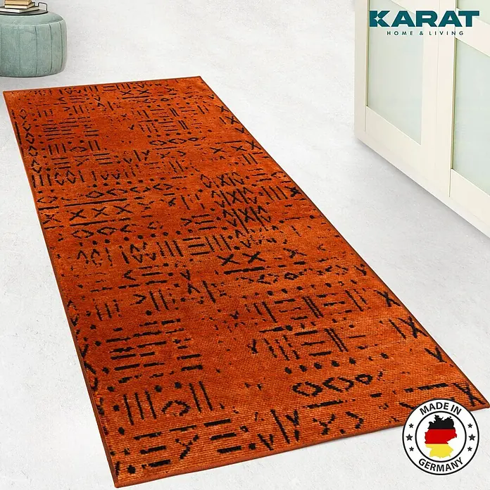 Teppichläufer Vena - Terra, 100 x 80 cm, 65 % Baumwolle, 35 % Polyester - Ein orangefarbener Teppich mit schwarzen Mustern, der das "OEKO TEX"-Siegel und das "Made in Germany"-Zeichen trägt.