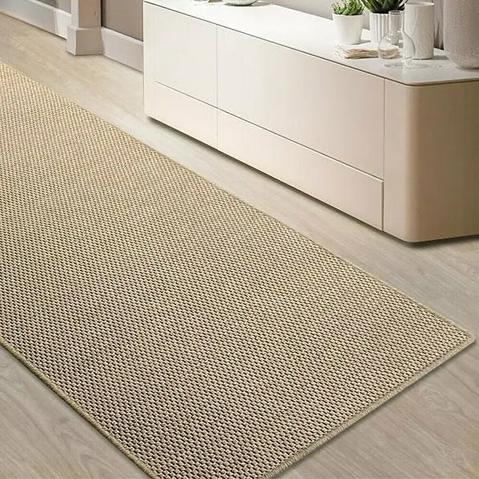 Flachgewebeteppich Kalkutta - Beige, 100 x 100 cm, 83 % Polypropylen, 17 % Naturfaser - Ein beigefarbener Läufer mit gewebter Textur liegt auf einem hellen Holzboden vor einem weißen Sideboard.