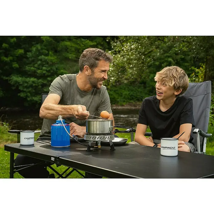 Campingaz Campingkocher Camp & Trek Connect CV - Anzahl Brenner: 1 Stk., 2 kW - Campingaz Kocher im Einsatz: Vater und Sohn bereiten am Tisch im Freien ein Gericht zu.
