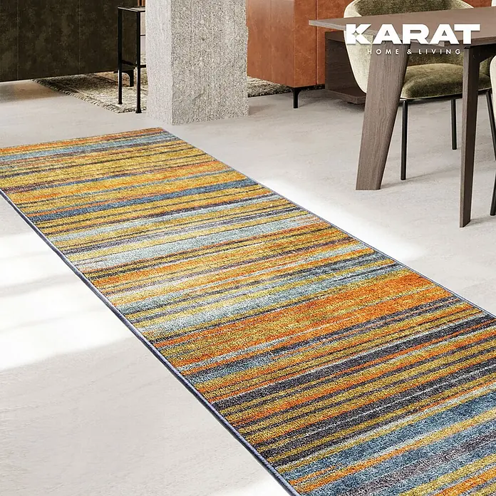 Teppichläufer Calama - Bunt, 250 x 80 cm, 100 % Polyamid - Ein langer Läuferteppich mit bunten Streifen in Gelb-, Orange- und Blautönen liegt in einem modern eingerichteten Raum.