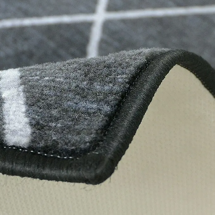 Teppichläufer Cosenza - Schwarz, 450 x 80 cm, 100 % Polyamid - Detailaufnahme eines grauen Teppichs mit Karomuster und einer dunklen, sauber vernähten Kante.