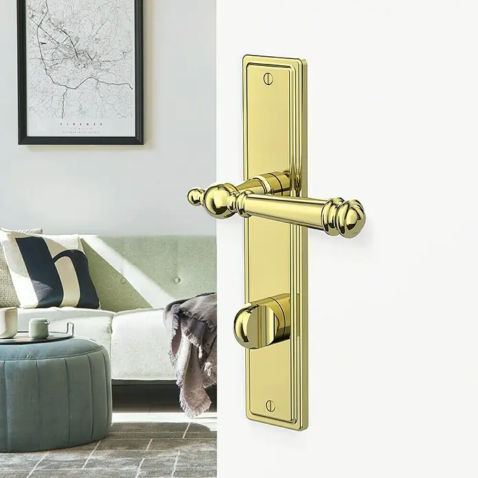 Diamond Doors Classic Drückergarnitur WC Classic Indiana - Schlitzkopf/Olive, Sonstiges - Nahaufnahme einer eleganten goldenen Türgarnitur mit Hebelgriff und Drehknopf auf einer weißen Tür.