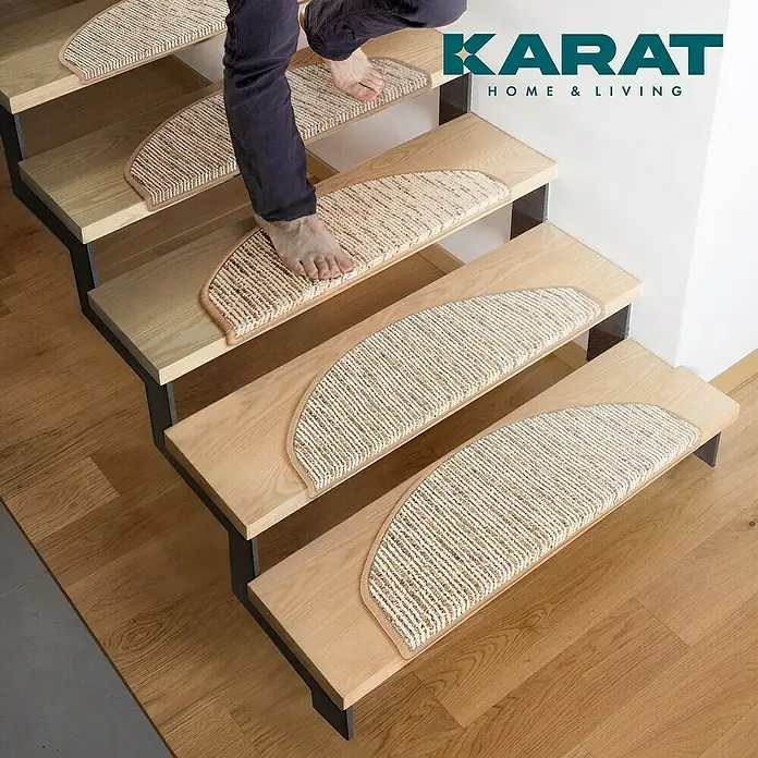 Stufenmatte Geneva - 65 x 23,5 cm, Beige, Halbrund - Teppichstufenmatten auf einer Holztreppe mit dem Aufdruck „KARAT HOME & LIVING“.