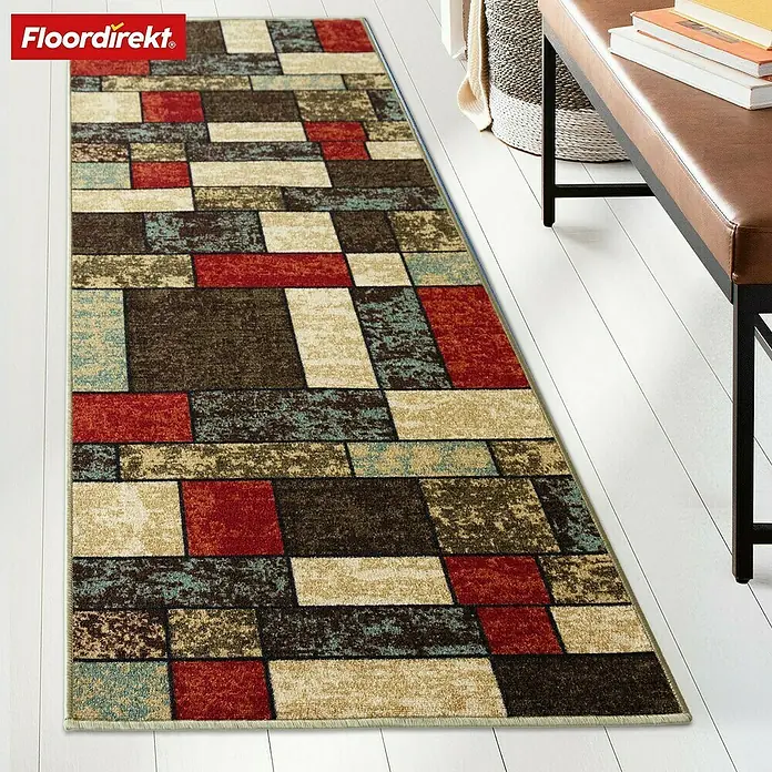 Teppichläufer Mannheim - Patch, 100 x 80 cm, 100 % Polyamid - Ein Läuferteppich mit geometrischem Muster aus Rechtecken in Rot, Braun, Beige und Blau liegt auf einem Holzboden.
