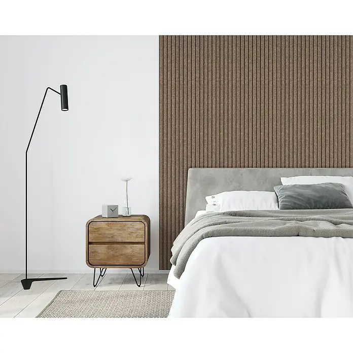 Lautloz Akustikpaneel Coverz - Coffee, 20 x 240 cm, Textil - Schlafzimmer-Szene mit Nachttisch aus Holz, Stehlampe und Bett vor einer Akustikpaneelwand. Das Produkt ist ein moderner Nachttisch.
