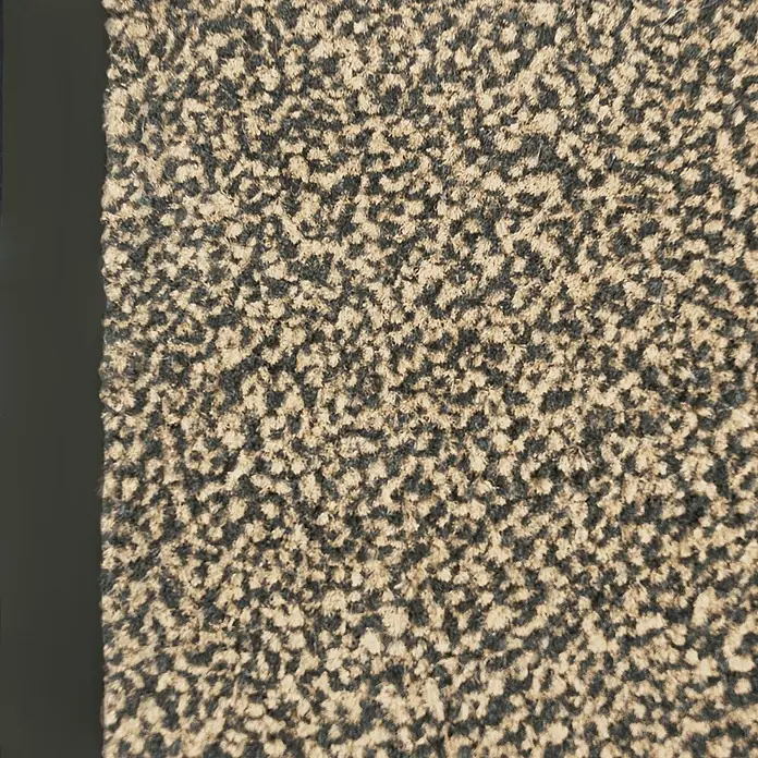 Fußmatte Sky - Ocker/Schwarz, 300 x 120 cm, 100 % Polypropylen - Nahaufnahme eines zweifarbigen Fußabtreters mit unregelmäßigem Punktmuster und einem schwarzen Rand auf der linken Seite.